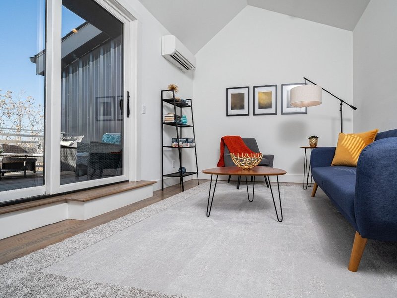 living room with large window, blue sofa and gray rug