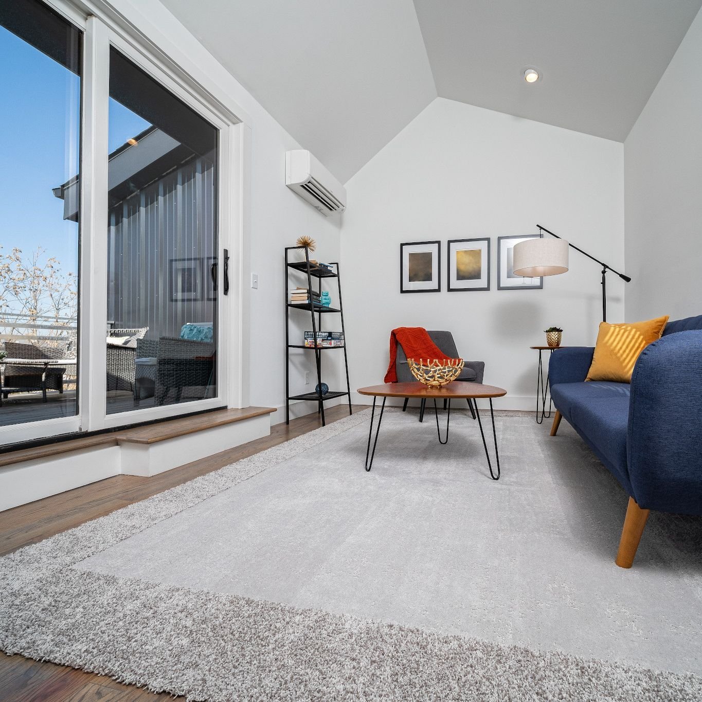 living room with large window, blue sofa and gray rug